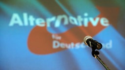 Ein Mikrofon steht auf einer Bühne vor dem AfD-Logo. Symbolbild