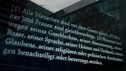 Eine Glasplatte mit dem eingravierten Text von Artikel 3 des Grundgesetzes steht am Jakob-Kaiser-Haus des Deutschen Bundestages in Berlin.