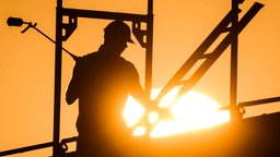 Symbolbild: Ein:e Bauarbeiter:in mit einem Gasbrenner auf einer Baustelle
