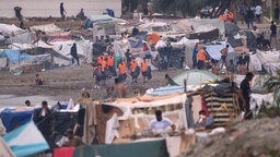 Flüchtlinge stehen in der Nähe ihrer Zelte am Strand von El Trampolín in der spanischen Exklave Ceuta.(02.09.2026).