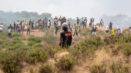 Ein marokkanischer Polizist schaut zu, wie Migranten aus Marokko in die spanische Enklave Ceuta gelangen.