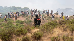 Ein marokkanischer Polizist schaut zu, wie Migranten aus Marokko in die spanische Enklave Ceuta gelangen.