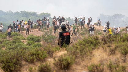 Ein marokkanischer Polizist schaut zu, wie Migranten aus Marokko in die spanische Enklave Ceuta gelangen.