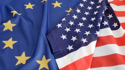 Eine US-Flagge und eine Europa-Flagge liegen nebeneinander.