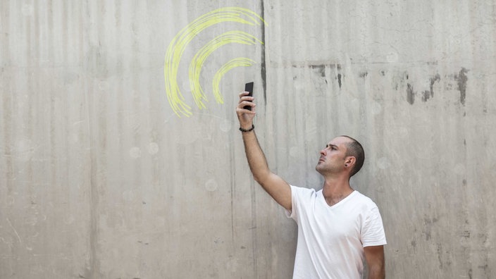 Symbolbild: Ein Mensch hält ein Smartphone auf der Suche nach einer guten Verbindung nach oben.