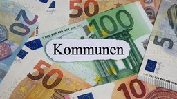 Auf Geldscheinen liegt das Wort Kommunen. Symbolbild: Finanzkrise der Kommunen