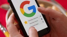 Symbolbld: Smartphone mit Google-Bewertungs-Screen.