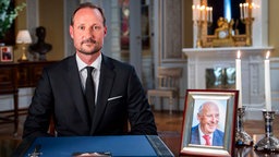 Norwegens König Haakon neben dem Bild des versorbenen Königs Harald (29.08.2026).