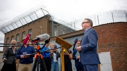 Benjamin Limbach (r, Bündnis 90/Die Grünen), Justizminister von Nordrhein-Westfalen, steht bei einem Pressestatement zu den Vorgängen in der JVA Siegburg im Eingangshof der Anstalt.