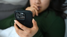 Ein junges Mädchen schaut etwas auf einem Smartphone.