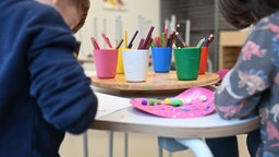 Symbolbild: Zwei Kinder sitzen an einem Tisch und basteln.