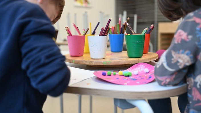 Symbolbild: Zwei Kinder sitzen an einem Tisch und basteln.