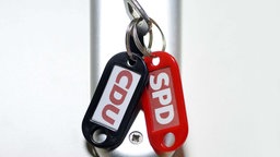 Symbolbild: Schlüsselanhänger mit SPD- und CDU-Schriftzug.