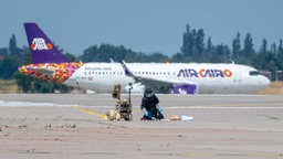 Einsatzkraft mit Schutzanzug an der unbekannten Drohne auf dem Leipziger Flughafen (05.08.2026).