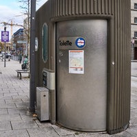 Eine öffentliche Toilette in der Innenstadt von Stuttgart, ausgestattet mit einem Zugangssystem und Informationen zu weiteren Standorten. 