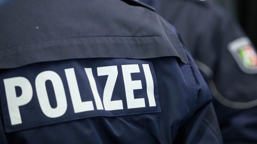 Rückansicht eine Menschen, Jacke mit Schriftzug "Polizei"