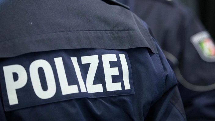 Rückansicht eine Menschen, Jacke mit Schriftzug "Polizei"