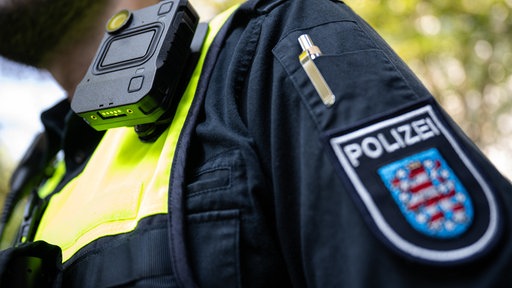 An der Weste eines Polizisten ist eine Bodycam befestigt.