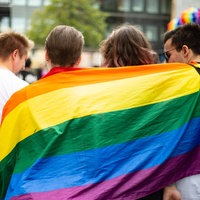 Vier junge Menschen mit Regenbogenfahne auf dem CSD am 5.8.2023 in Nuernberg.
