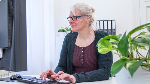 Symbolbild: Grauhaarige, ältere Frau bei Büroarbeiten am PC.