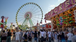 Besucher auf der Düsseldorfer Rheinkirmes 2026. Im Hintergrund ist das Riesenrad zu sehen.