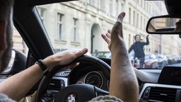 Symbolbild: Ein Autofahrer und ein Mensch auf dem Fahrrad gestikulieren mit den Händen.