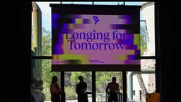 Presskonferenz zur Ruhrtriennale 2026 vor einem Banner mit dem Motto "LONGING FOR TOMMORROW".