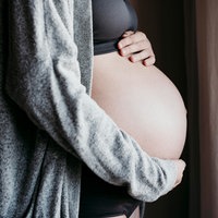 Schwangere Frau legt ihre Hände auf den Bauch