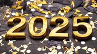 Eine goldene 2025 liegt zwischen Konfetti in schwarz und gold.
