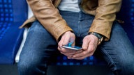 Symbolbild: Ein erwachsener Mensch nuzt ein Smartphone in einer S-Bahn.