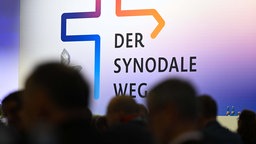  Teilnehmer der Synodalversammlung sitzen vor dem Schriftzug "Der Synodale Weg". 