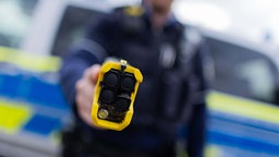 Symbolbild: Eine Polizekraft richtet einen Teaser auf sein Gegenüber.
