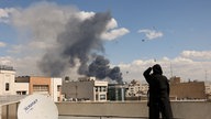 Eine Frau steht auf einem Dach in Teheran und blickt in die Richtung der Rauchwolke, die durch den Luftangriff der USA ausgelöst wurde.