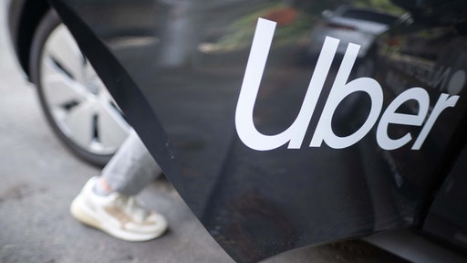 Symbolbild: Ein Mensch steigt in ein Auto mit "Uber"-Aufdruck