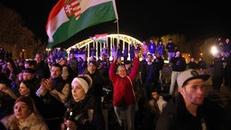 Besucher einer abendlichen Wahlkampfveranstaltung in Ungarn halten die Nationalflagge hoch.