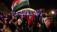 Besucher einer abendlichen Wahlkampfveranstaltung in Ungarn halten die Nationalflagge hoch.