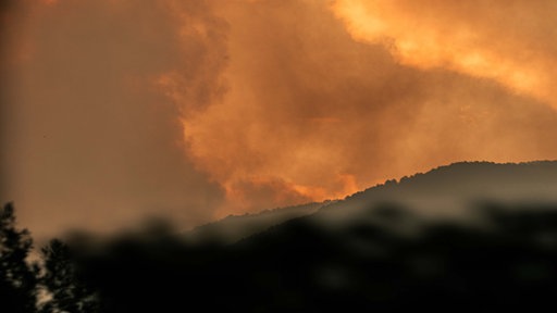 Symbolbild: Rotgefärbeter Rauch über brennenden Wäldern (Spanien 2026).