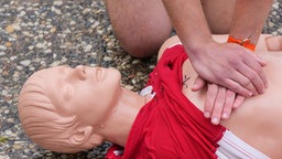 An einer Puppe wird die Herzdruckmassage gezeigt. Symbolbild