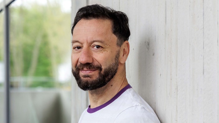 Selim Özdogan lächelt von der Seite in die Kamera. 