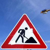 Ein Baustellenschild steht vor Kränen in der Straße Unter den Linden in Berlin-Mitte.