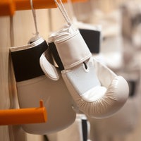 Weiße Boxhandschuhe hängen an einer Garderobe in einem Trainingsraun
