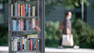 Ein offener Bücherschrank steht auf einer Freifläche in Frankfurt. 