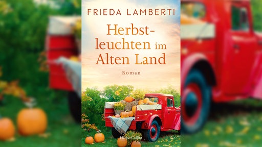 Das Cover von Frieda Lambertis Roman "erbstleuchten im Alten Land"zeigt eine ländliche Idylle mit grünen Wiesen, Blumen und einem zentral platzierten roten Oldtimer-Lastwagen, beladen mit Kürbissen.