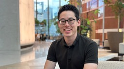Das Foto zeigt Dennis-Kenji Kipker mit dunklen, nach hinten gekämmten Haaren, einer schwarzen Brille und einem breiten Lächeln.