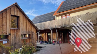 Schultaschen stehen aufgereiht an der Außenwand des mit Solarpanelen bedeckten Schulgebäudes der "Draußenschule" in Ladenburg