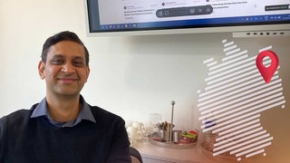 Shivansh Tyagi ist ein junger indischer Mann. Er sitzt in einem Büro – daneben ist als Logo der Deutschlandreportage die Deutschlandkarte mit einer Markierung in Berlin zu sehen.