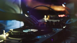 Detailaufnahme eines DJs, der auf einer Party mit Schallplatten auflegt.