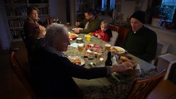 Familie Oppenlander sitzt an einem Tisch beim Essen. 