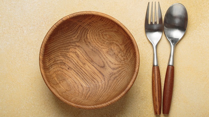 Symbolbild zur Fastenzeit: Eine Gedeck mit leerer Holzschüssel und Holzbesteck