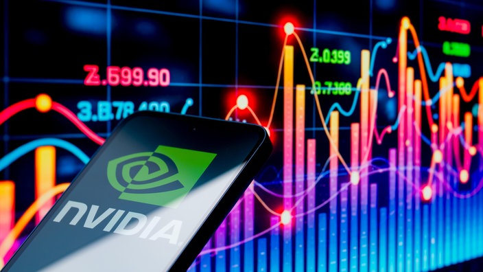 Detailaufnahme eines Smartphones auf dessen Bildschirm das Logo des KI-Konzerns "Nvidia" zu sehen ist; im Hintergrund eine bunte grafische Darstellung eines Aktienkurses.